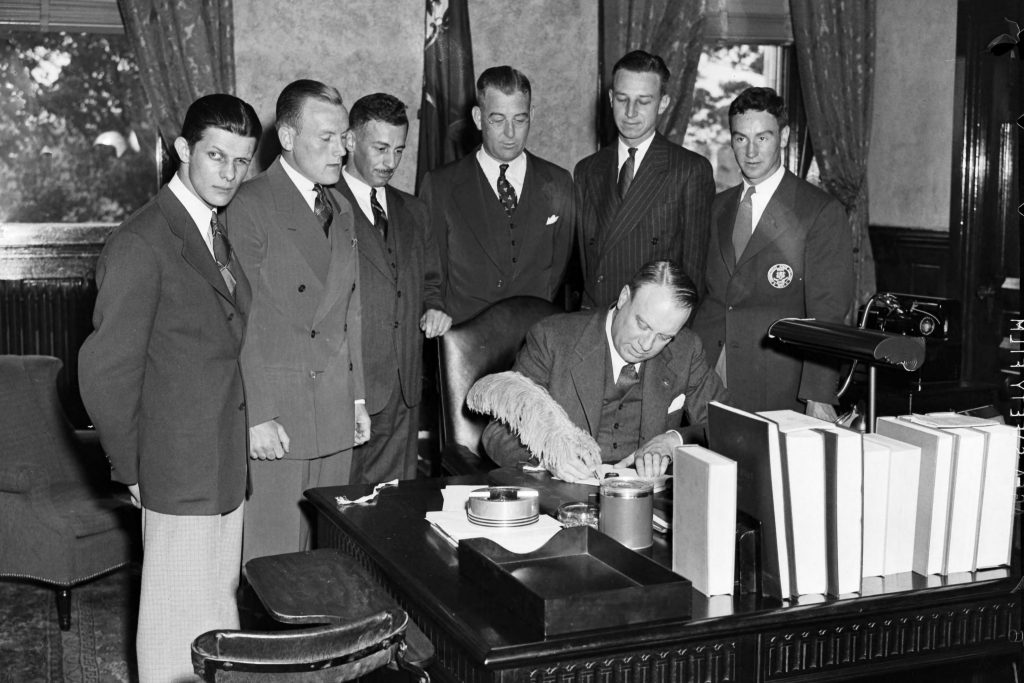 Gov. Raymond Baldwin, center, signs the bill establishing Connecticut State College as The University of Connecticut on May 26, 1939. Looking on are, left to right: Normand P. DuBeau of Willimantic, editor-in-chief of The Connecticut Campus; William Crowley of New Britain, president of the Student Senate; Andre Schenker, professor of history; President Albert N. Jorgensen; George Pinckney, alumni secretary; and Edward Finn of Hartford, a student. (Photo courtesy of University Archives)