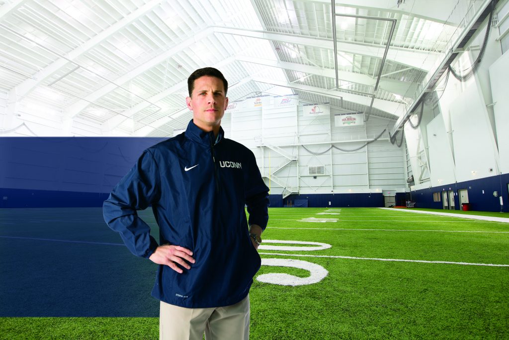 Head football coach Bob Diaco in the Schenkman Football Facility. A gift from Diaco and his wife Julia will help fund new facilities for other sports at UConn. (Stephen Slade '89 (SFA) for UConn)