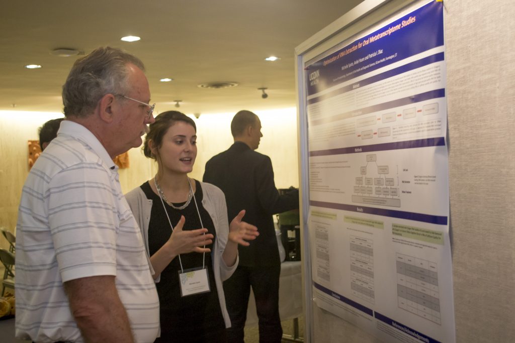 PhD student Michelle Spoto explaining her research poster to reconstructive sciences researcher Alex Lichtler during the Skeletal, Craniofacial and Oral Biology annual symposium Monday at UConn Health. (Photo by Tina Encarnacion)