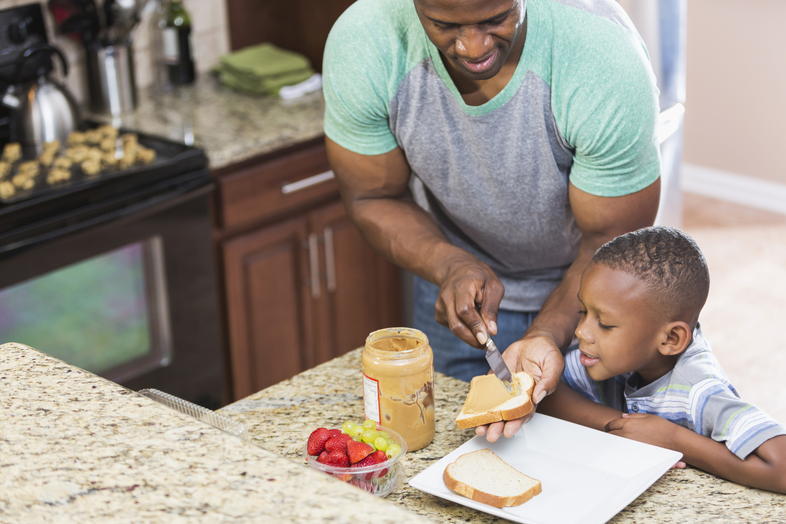 An African American father makes a peanut butter sandwich for his 5 year-old son's lunch. (iStock Photo)