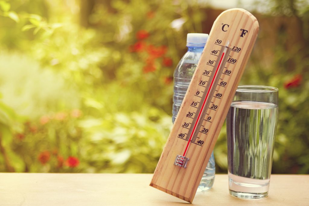 Thermometer on summer day showing high temperature over 100 degrees F, and glass of water. (iStock Photo)