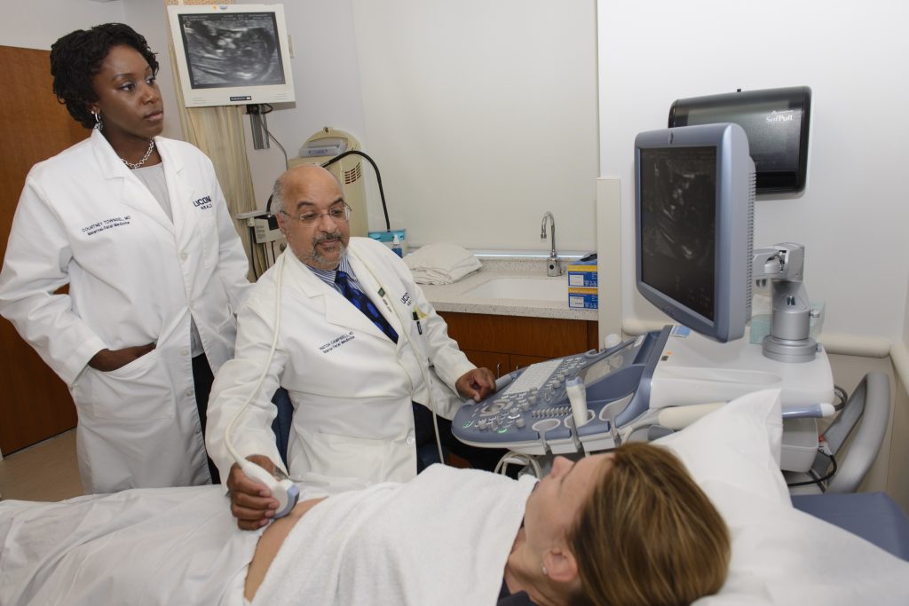 Dr. Courtney Townsel, left, looks on as Dr. Winston Campbell performs an ultrasound on an expectant mother. (Janine Gelineau/UConn Health Photo)