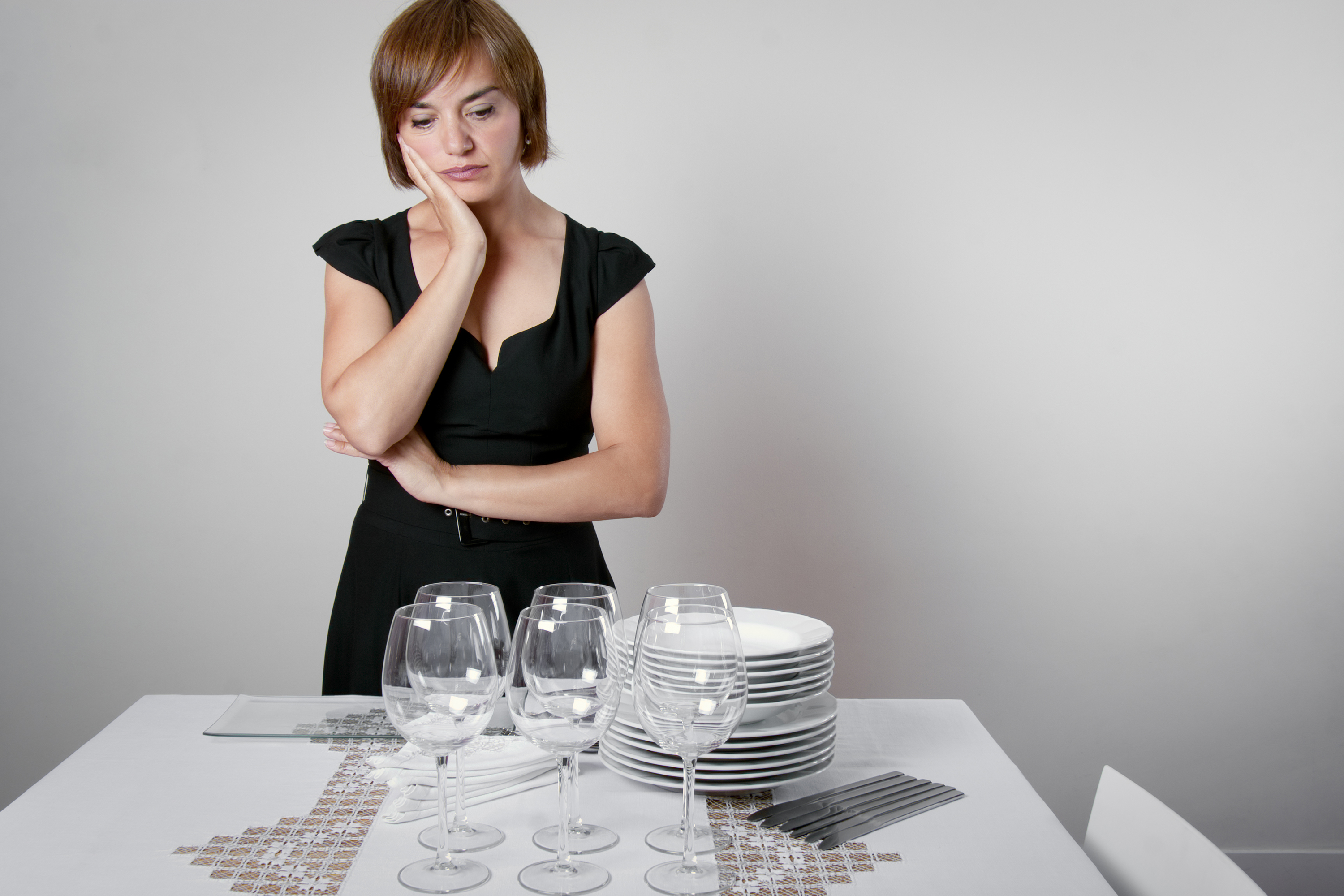Worried woman setting the table for a celebration. (ASIFE, Getty Images)