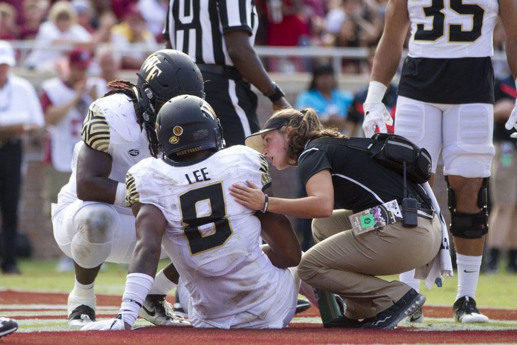 An athletic trainer attends to an injured football player. (Photo by Logan Stanford/Icon Sportswire via Getty Images)