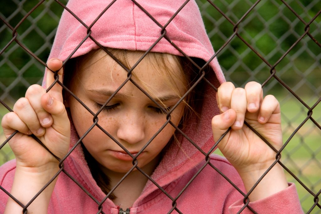 Unhappy girl behind a fence. (Getty Images)