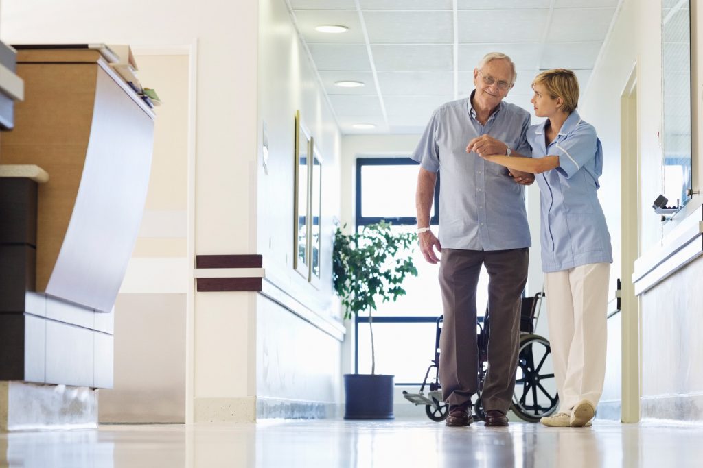A senior patient begins to walk a hospital hallway with help from a nurse. (Getty Images)