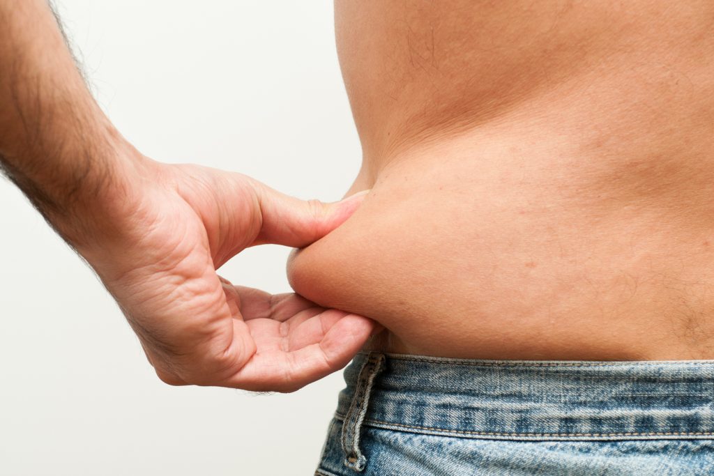 Close up shot of a man pinching fat from his belly. (Getty Images)