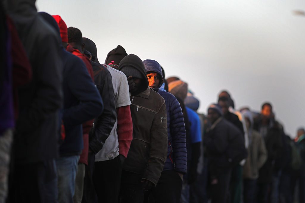 Migrants queue to board buses and leave the notorious 'Jungle' camp in Calais, France, before authorities demolished the site in fall 2016 in Calais, France. Some 7,000 people were estimated to be living in the camp in squalid conditions. (Christopher Furlong/Getty Images)