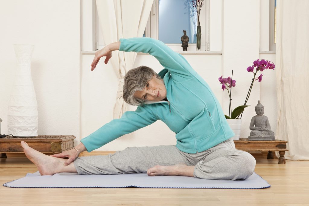 A senior woman stretching at a yoga studio. (Getty Images)