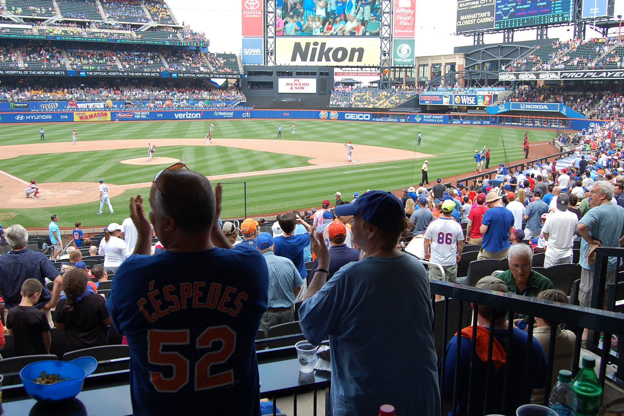 A participant in the River House Baseball Reminiscence Program and her son cheer on the Mets at Citi Field. (Kenneth Best/UConn Photo)