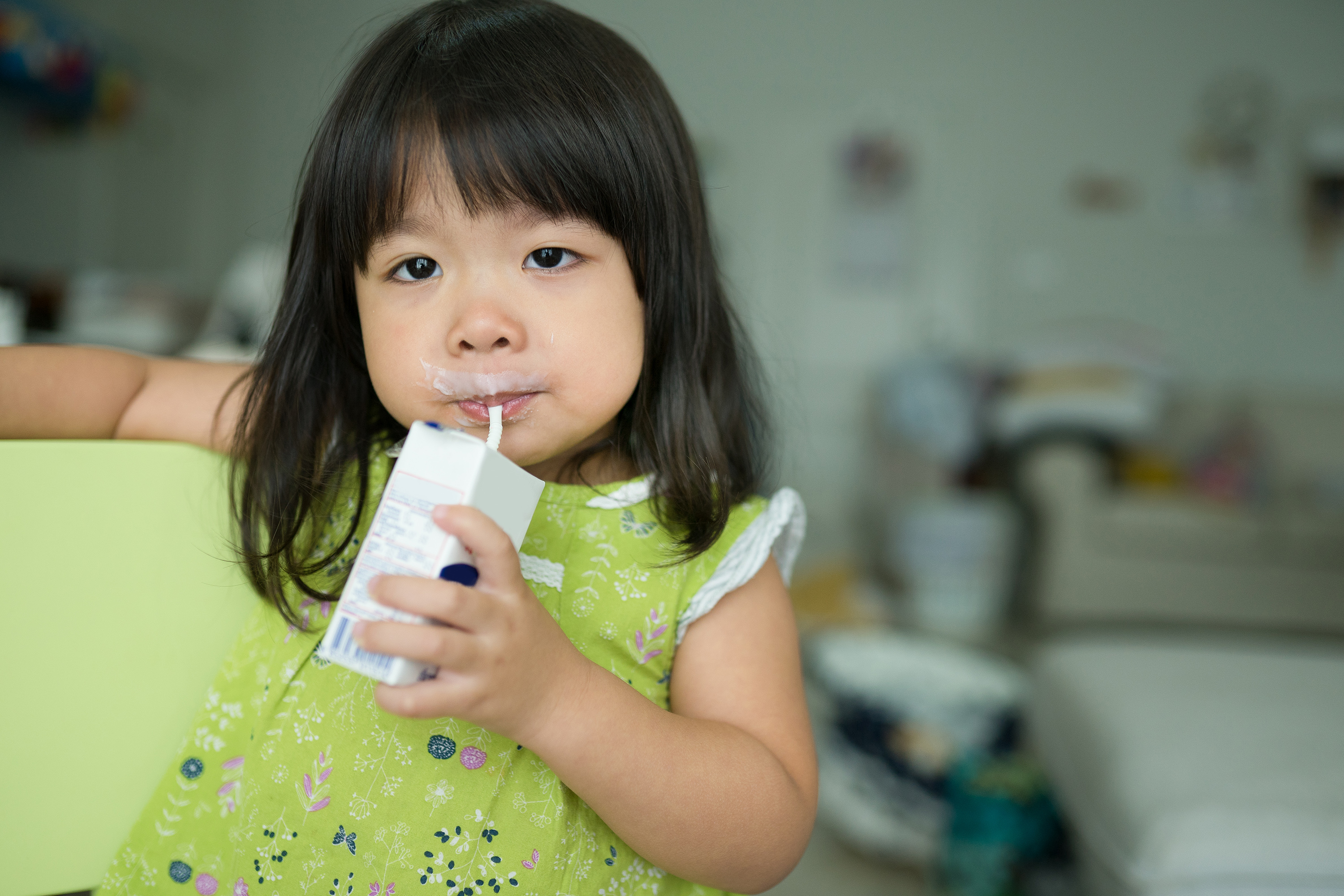 A child drinking a small carton of milk. (Shutterstock)