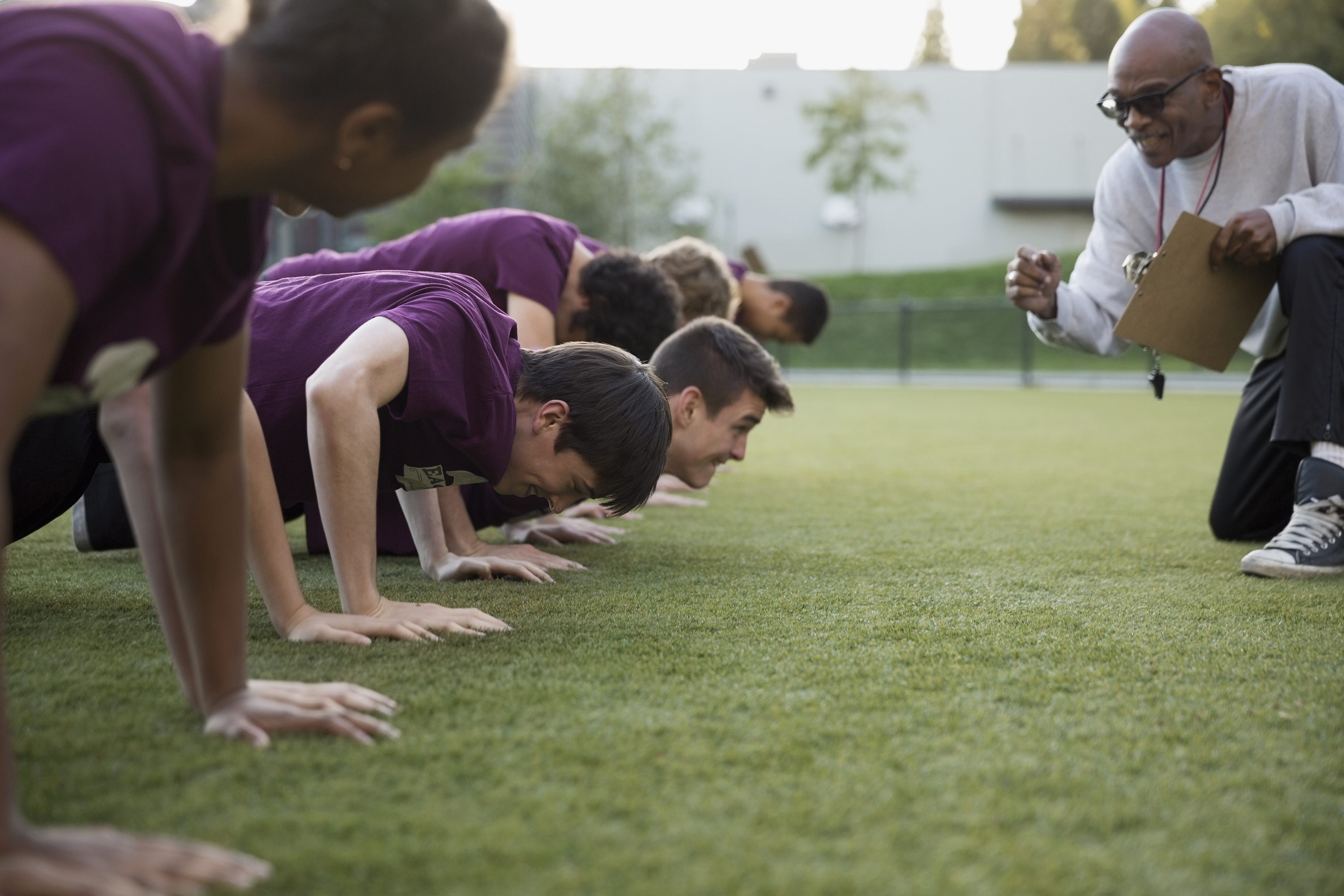 Physical education teacher encouraging students doing push-ups. (Hero Images via Getty Images)