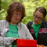 Laurie Doss, left, of Kent Land Trust and Marvelwood School, and Lillian Steinmayer of Marvelwood School, practice using geospatial technology in the UConn Forest. The activity was part of the NRCA's Conservation Training Partnerships program, in which teams of teens and adults take part in a two-day conservation workshop and project. (NRCA Staff/UConn Photo)