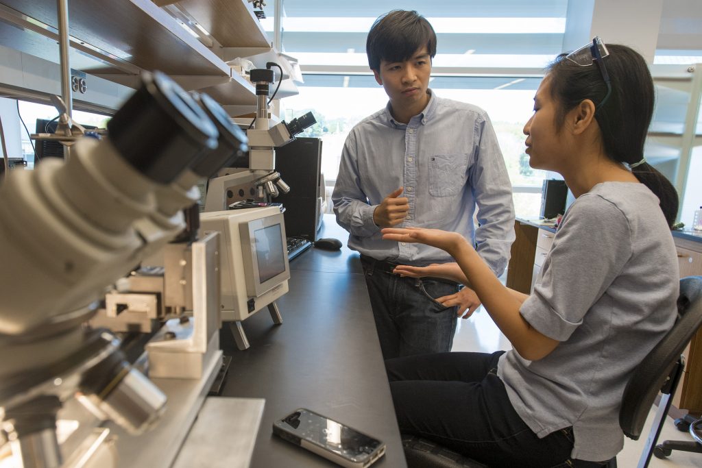 Professor Thanh Nguyen, left, speaks with Khanh Tran, a Ph.D. student, about a novel additive manufacturing process he invented that can deliver multiple doses of a vaccine at specific time intervals with just one injection. (Sean Flynn/UConn Photo)