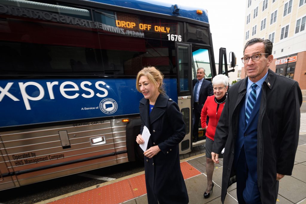 President Susan Herbst, left, greets Lt. Gov. Nancy Wyman, and Gov. Dannel Malloy as they arrive on a CT Express bus at the Nash-Zimmer Transportation Center on Nov. 13, 2017. (Peter Morenus/UConn Photo)