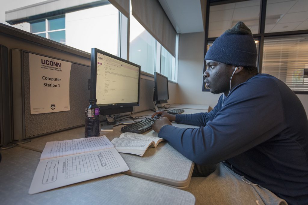 Student-athlete Foluronso ‘Foley’ Fatukasi, Football , writing a paper in the study lounge of the Burton Football Complex. (Sean Flynn/UConn Photo)