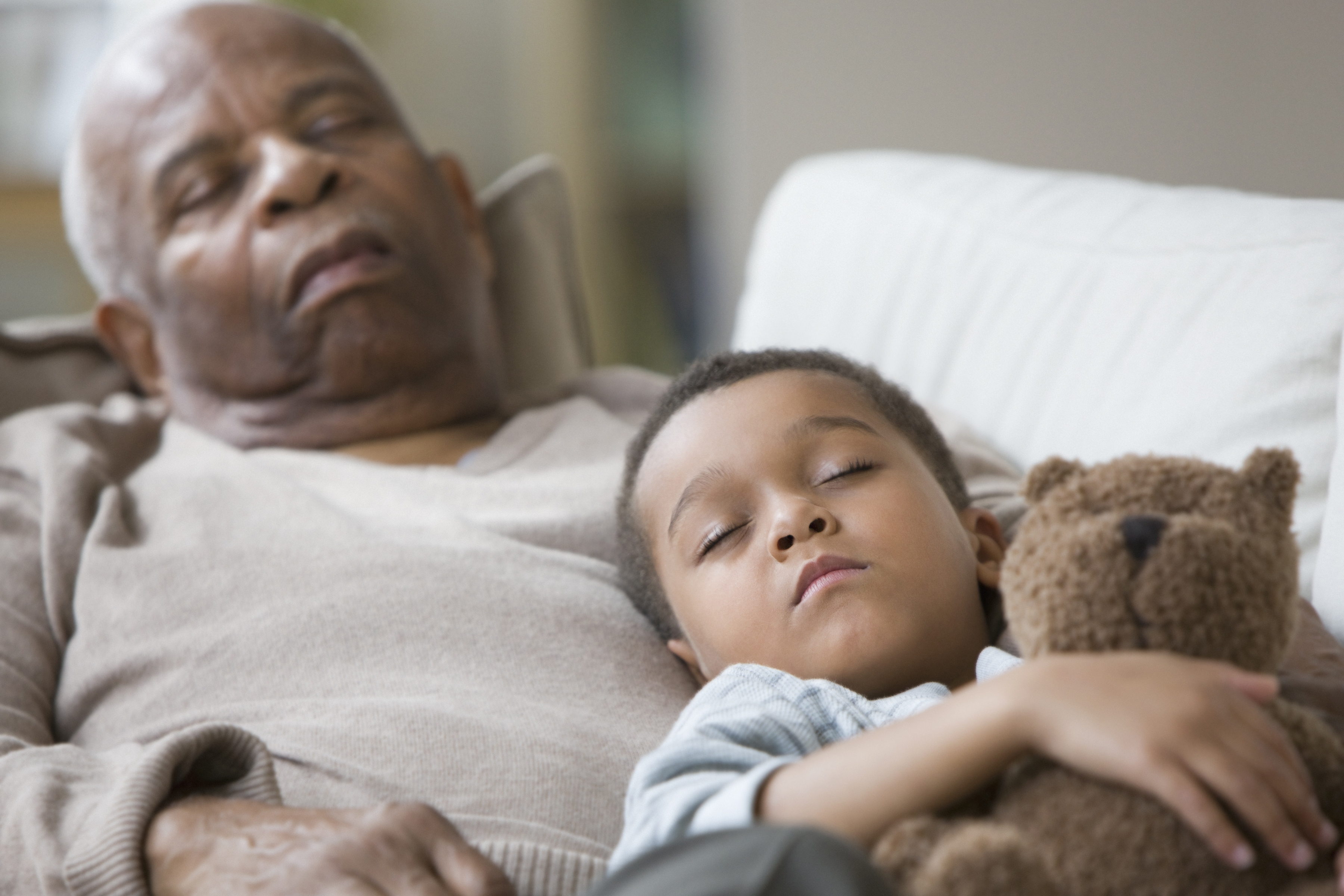 Grandfather and grandson taking a nap together on the couch. (Getty Images)
