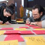 Lauren Graham '18 (CLAS), left, and Zachary Corolla '18 (CLAS) write their ideas on combating racism onto paper leaves at a table hosted by the USG Student Development Committee during a Metanoia event titled 'Leaf A Mark.' (Peter Morenus/UConn Photo)