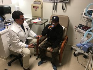 Dr. Mario Perez looks on as a study participant takes a lung function test. (Lauren Woods/UConn Health Photo)