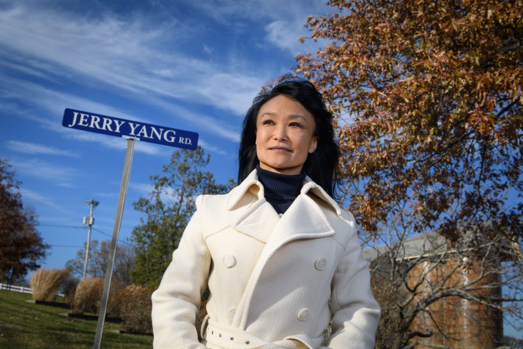 Xiuchun 'Cindy' Tian stands next to a roadsign bearing the name of her late husband, UConn researcher Jerry Yang, who is known for his pioneering work in animal cloning. (Peter Morenus/UConn Photo)