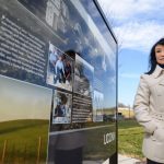 Animal science professor Cindy Tian stands next to a sign depicting Jerry Yang and agricultural research at UConn. (Peter Morenus/UConn Photo)