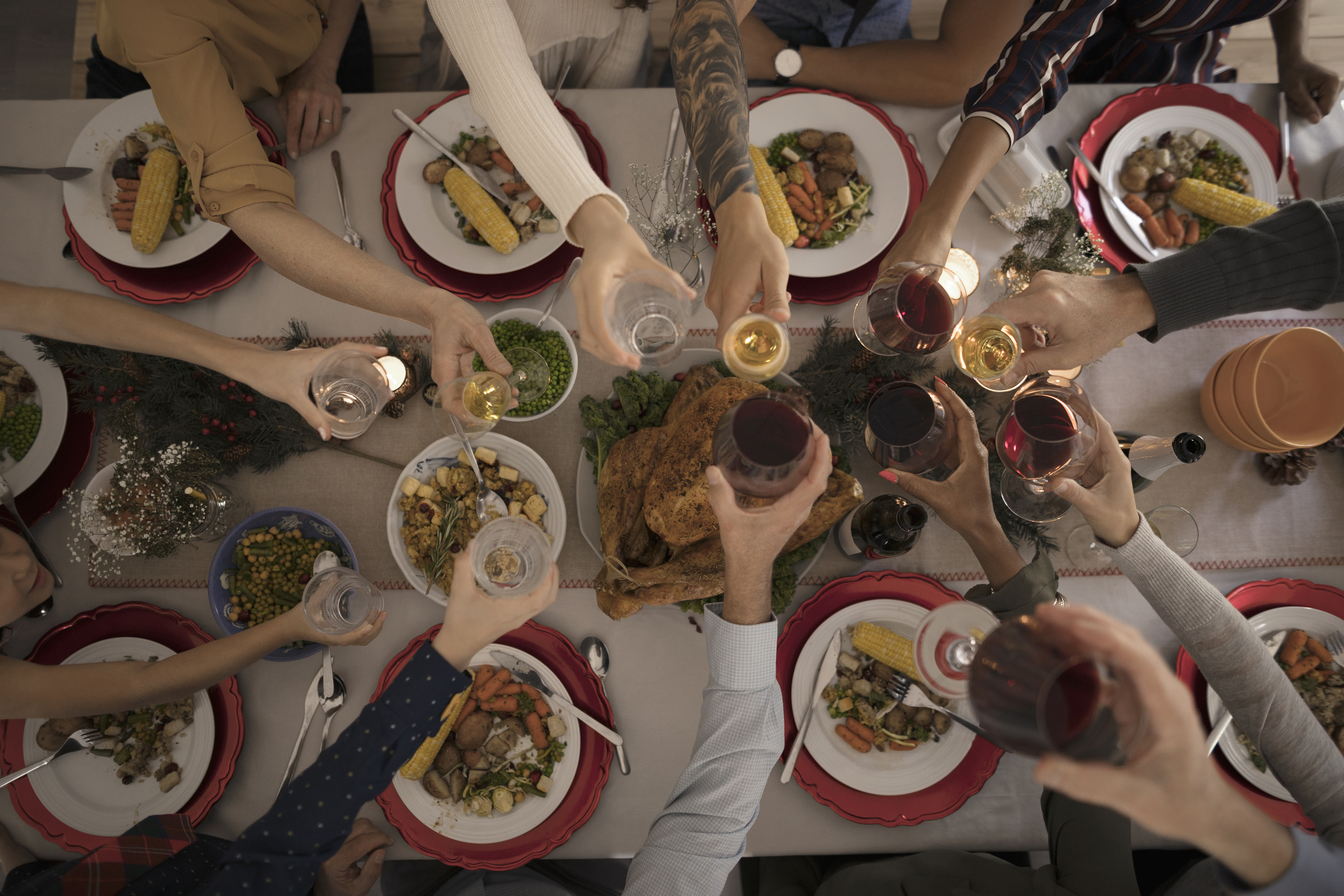 Overhead view family toasting wine glasses at candlelight Christmas turkey dinner at table. (Hero Images/Getty Images)