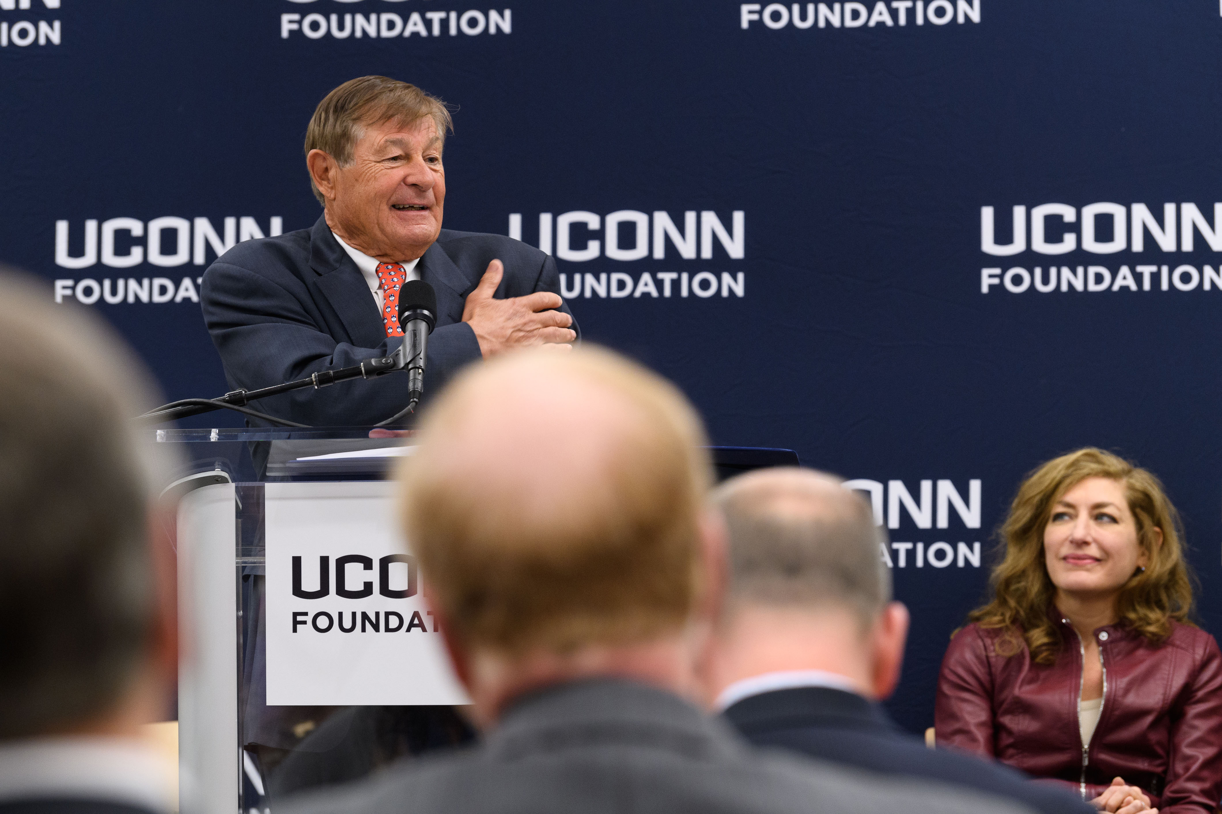 Peter J. Werth speaks at an event to announce his $22.5 million commitment to the University and the naming of the Peter J. Werth Residence Tower on Dec. 4, 2017. Seated is President Susan Herbst. (Peter Morenus/UConn Photo)