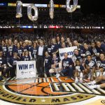 Members of the Women's Basketball team past and present celebrate the 1,000th win for Geno Auriemma and Chris Dailey at the Mohegan Sun Arena on Dec. 19. The current team held up pictures of the two coaches from 1985. (Gallery photos by Stephen Slade '89 (SFA) for UConn)