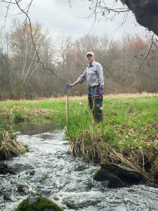 Professor John Clausen installing a stage sampler water collector device in the Conantville Brook. (Submitted)