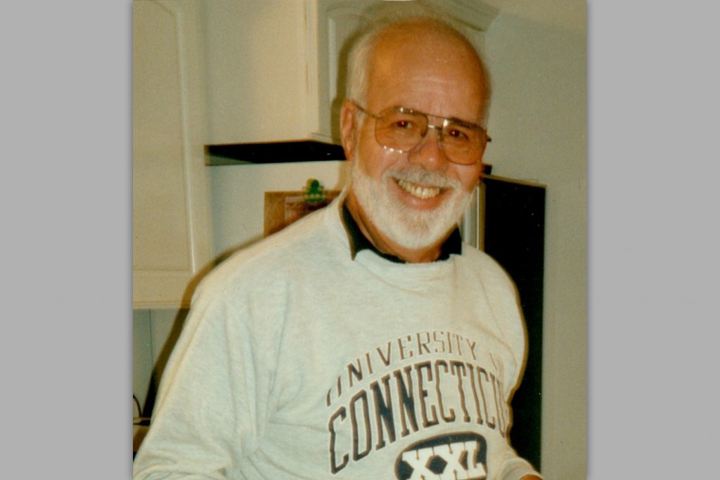 Vintage head shot of Antonio Romano wearing a UConn sweatshirt.