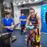 Laura Marcoux '10 (CLAS) rides a stationary bicycle for two hours in a hot and humid environment inside the Mission Heat Lab at Gampel Pavilion on Jan. 19, as graduate students Courtney Benjamin, left, and Yasuki Sekiguchi look on. (Peter Morenus/UConn Photo)
