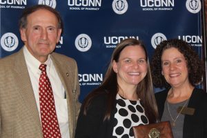 Amanda Williams, Adjunc Faculty Preceptor of the Year for APPE. Joined at the podium by Dennis J. Chapron and Jill Fitzgerald.