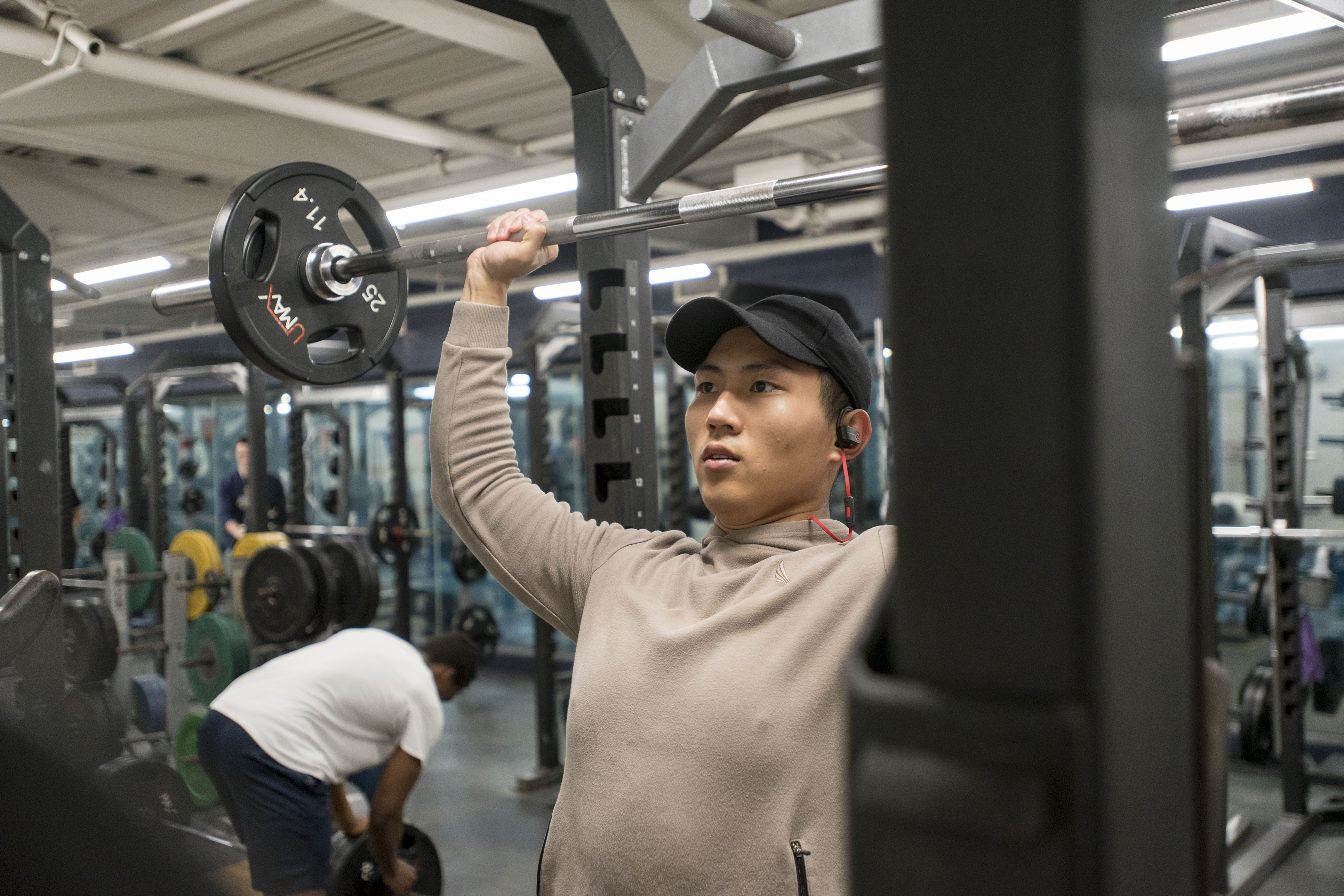 International student Jiazhen Huang ’18 (CLAS), a sport promotion major, lifts weights at the Student Recreational Facility on Feb. 22, 2018. (Sean Flynn/UConn Photo)