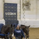 Sage Saffran '19 (CAHNR), an animal science major, walks two polo ponies (as the horses are known) before the UConn Men's and Women's Polo Match versus Kentucky on Feb. 3, 2018. The door with the legend UConn represents the goal. (Garrett Spahn '18 (CLAS)/UConn Photo)
