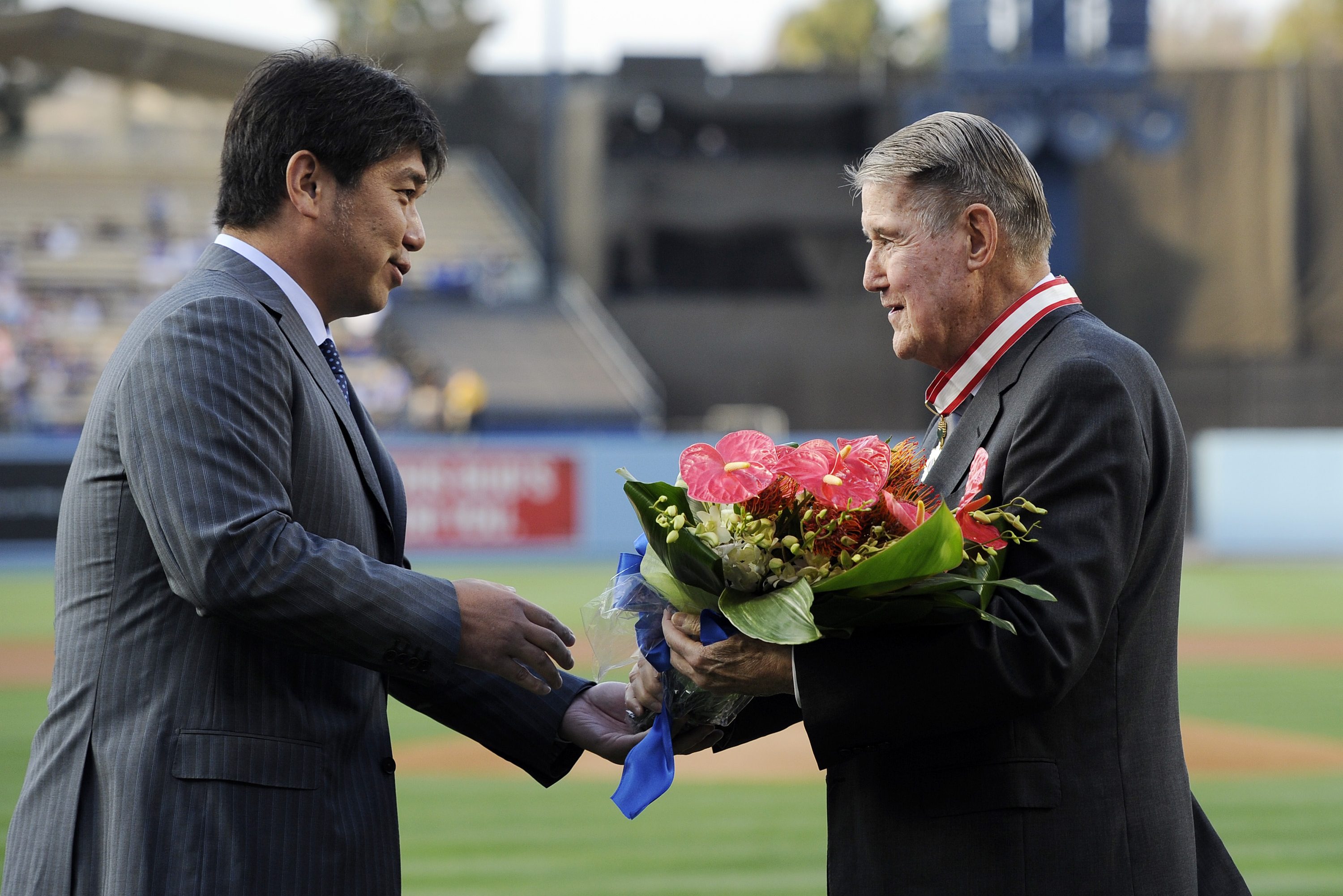 Former Los Angeles Dodgers pitcher Hideo Nomo, presents flowers to former Dodgers President Peter O'Malley (R) after he received The Order of the Rising Sun, Gold Rays with Neck Ribbon from Harry H. Horinouchi, consul general of Japan in Los Angeles, as part of Japan Night celebration at Dodger Stadium prior to the start of a baseball game between the Dodgers and the Philadelphia Phillies July 8, 2015 at Dodger Stadium in Los Angeles, California. (Photo by Kevork Djansezian/Getty Images)