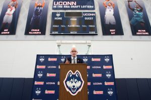 Head coach Dan Hurley greets the media and the university community against a backdrop depicting former Huskies who were drafted to the NBA.