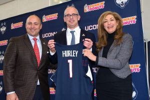 Dan Hurley holds up his UConn Hurley 1 shirt, flanked by athletic director David Benedict, left, and President Susan Herbst.