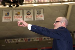 Dan Hurley points to a display celebrating the Huskies' tradition of success in Gampel Pavilion after the event.