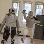 Freshman Michelle Martinez '21 (CAHNR), right, practices a move with senior Joanna Scuteri '18 (CLAS), a geoscience major. All fencers require a jacket, a mask, a glove, trousers or knickers, white stockings, flat-soled shoes, a body cord, and a weapon. (Garrett Spahn '18 (CLAS)/UConn Photo)