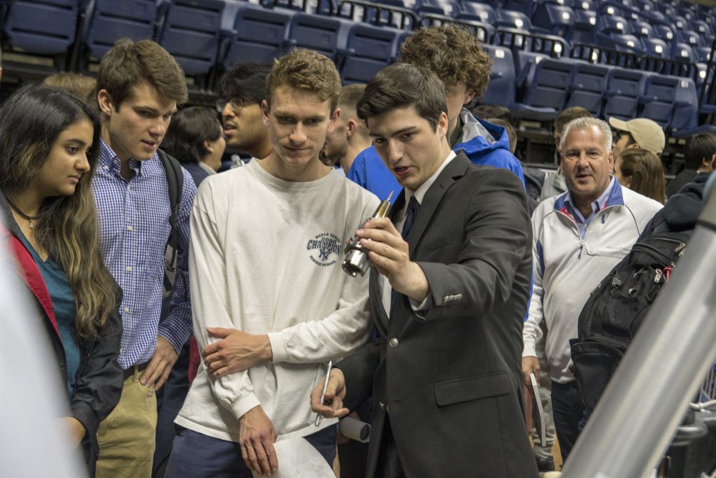 Mechanical engineering major Kyle Cabral '18 (ENG) shows how a robot is used to research an automated process to clean tool holders and reduce manual labor, during Senior Design Demonstration Day on April 27, 2018. (Garrett Spahn '18 (CLAS)/UConn Photo)