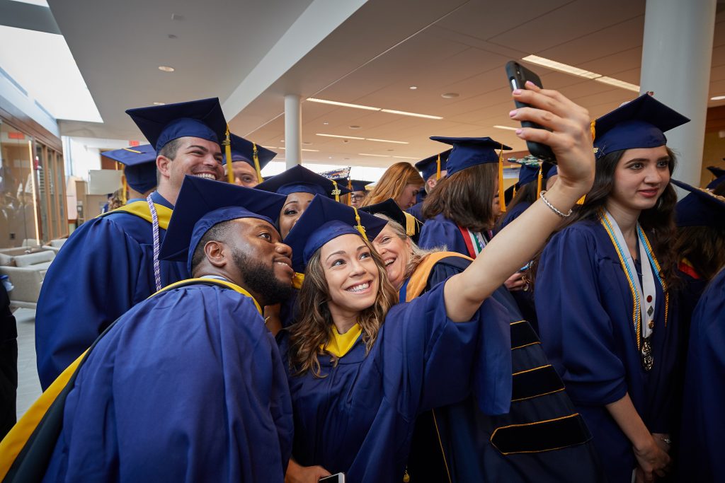 Bliss Dasilva '10 (CAHNR), '18 (NUR) takes a selfie with classmates at the Carolyn Ladd Widmer Wing of Storrs Hall before the start of the School of Nursing Commencement procession on May 5. (Peter Morenus/UConn Photo)
