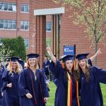 With arms raised, Sydney Gagne '18 (NUR), left, and Molly Gaffney '18 (NUR) walk along Glenbrook Road during the School of Nursing Commencement procession. (Peter Morenus/UConn Photo)