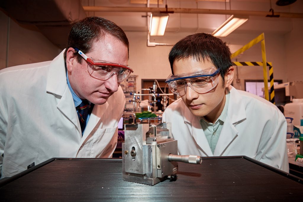 Michael Pettes, left, assistant professor of mechanical engineering, and Ph.D. student Wei Wu check a specially engineered device they created to exert strain on a semiconductor material only six atoms thick, on April 18, 2018. (Peter Morenus/UConn Photo)