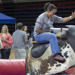 Angie Reyes of University Communications rides a mechanical bull during Employee Appreciation Day on May 10. (Sean Flynn/UConn Photo)