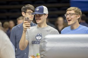 Ryan Casper '18 with phone and Matthew Ferraro '18, take pictures of a friend at Employee Appreciation Day. (Sean Flynn/UConn Photo)