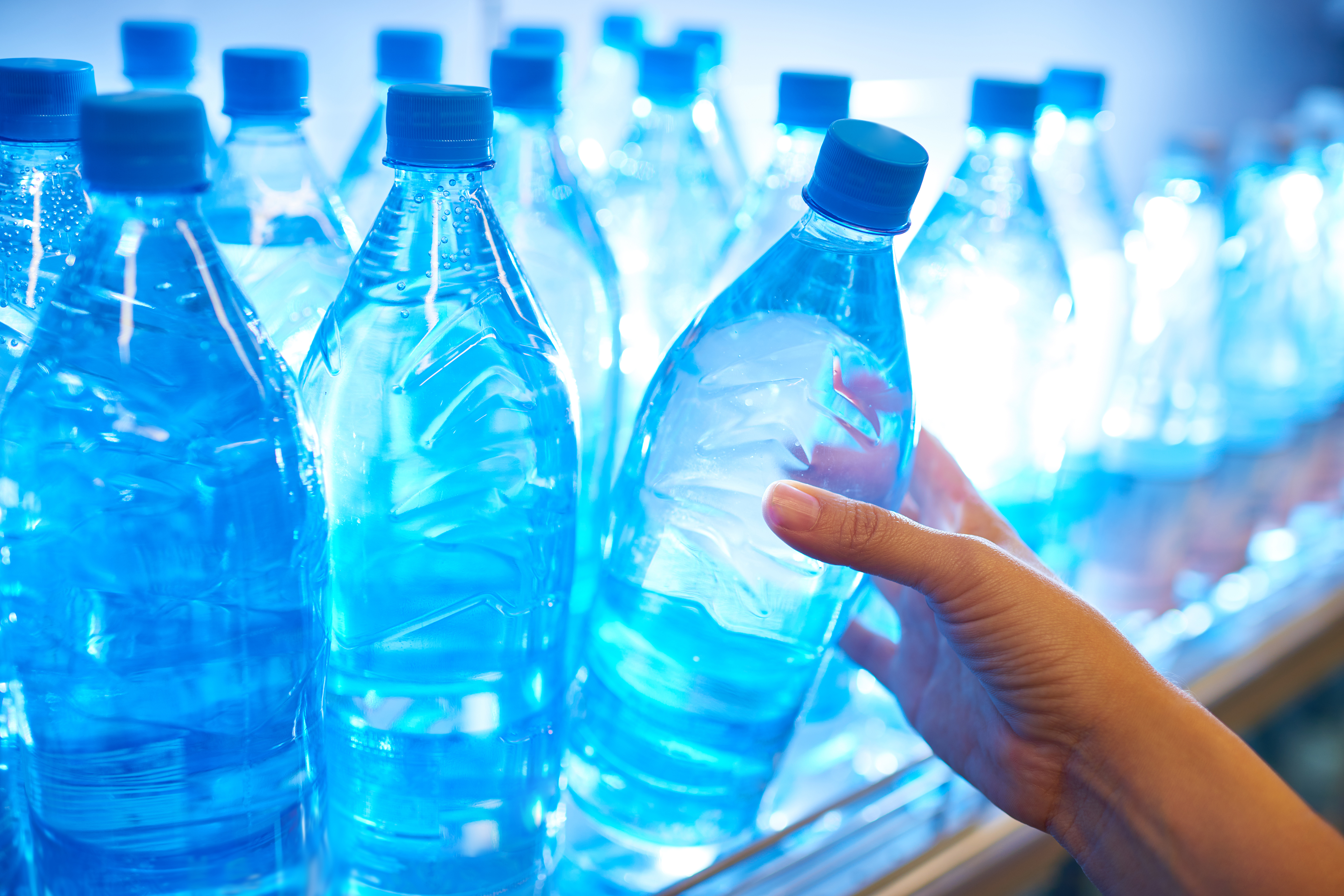 Human hand taking mineral water from shelf in supermarket. (Getty Images)