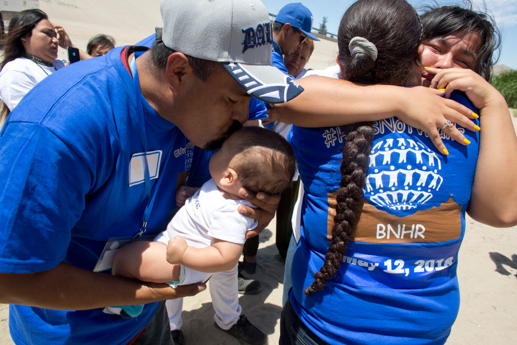 Migrant families embrace at the border between El Paso, Texas, and Juarez, Mexico. (Photo by Andrew Lichtenstein/Corbis via Getty Images)