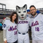 Sandra Francese, right, of Stamford, and Brian Francese '06 (BUS) with Jonathan the Husky at a New York Mets baseball game at Citi Field in Queens New York on June 3, 2018. (Peter Morenus/UConn Photo)