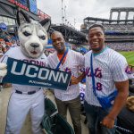Merlon Pinnock '15 MBA, center, and Oneil McCaulsky, both of Poughkeepsie New York with Jonathan the Husky at a New York Mets baseball game at Citi Field in Queens New York on June 3, 2018. (Peter Morenus/UConn Photo)