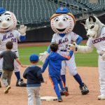 Jonathan the Husky, right, gives high fives to children during the Mr. Met Dash following a New York Mets baseball game at Citi Field in Queens New York on June 3, 2018. (Peter Morenus/UConn Photo)